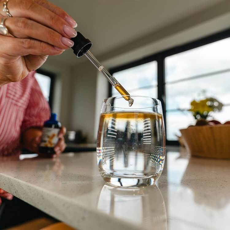 Tincture being dropped into water using a pipette.